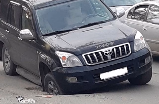 Дорожная ловушка: внедорожник провалился в яму на улице Петухова в Новосибирске